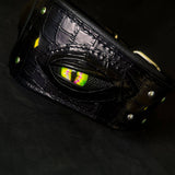 Close-up of the dragon eye on the Night Dragon leather dog collar, with croc-embossed black leather, silver studs and green crystals